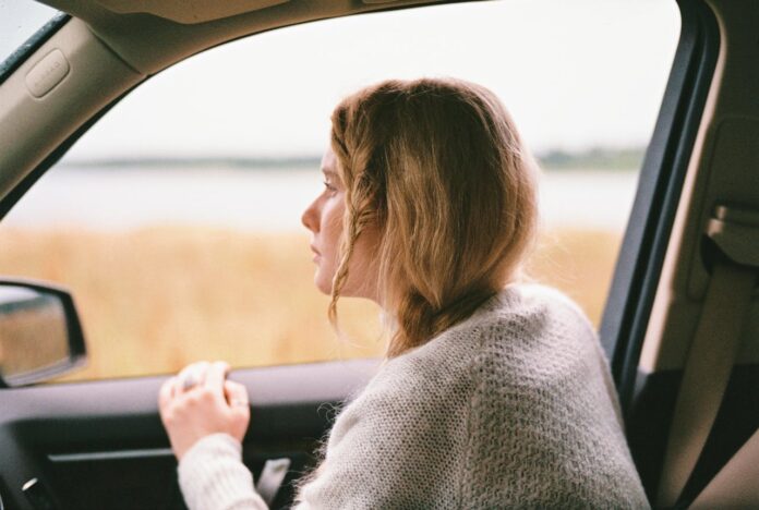 Women wearing sweater looking out a car window